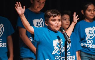 Young, male D.C. scores contestant in front of microphone