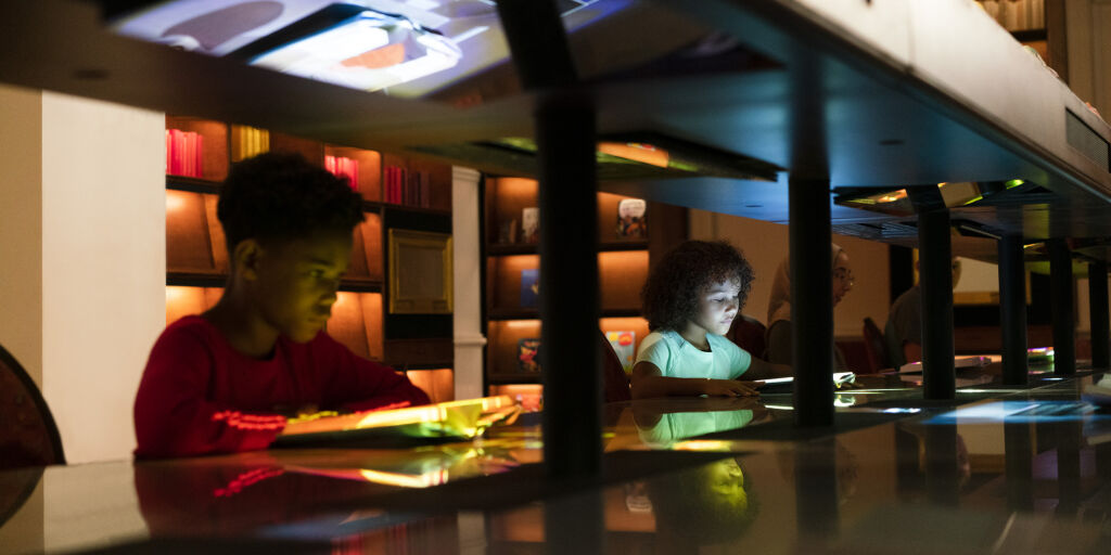 Children reading books on the Story Table in Planet Word's magic Library