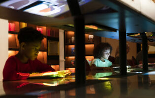 Children reading books on the Story Table in Planet Word's magic Library